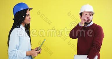 在一个<strong>黄色背景</strong>墙的工作室里，一位建筑师，一位非洲裔女士和一位戴着<strong>蓝色</strong>头盔的工程师